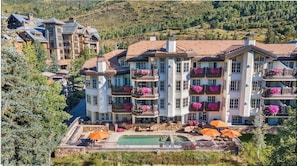 A multi-story hotel with balconies, a swimming pool, and outdoor seating.