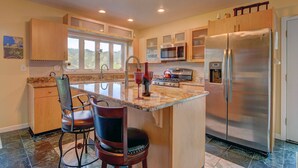 A modern kitchen with a central island, stainless steel appliances, and wooden cabinetry.