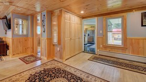 A spacious room with wooden paneling, a large window, and a view of the backyard.