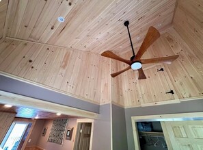 Una habitación con techo de madera, ventilador de techo y puerta que da a otra habitación.