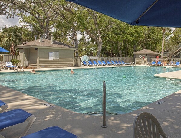 Relax by the pool surrounded by comfortable lounge chairs under a shaded area.