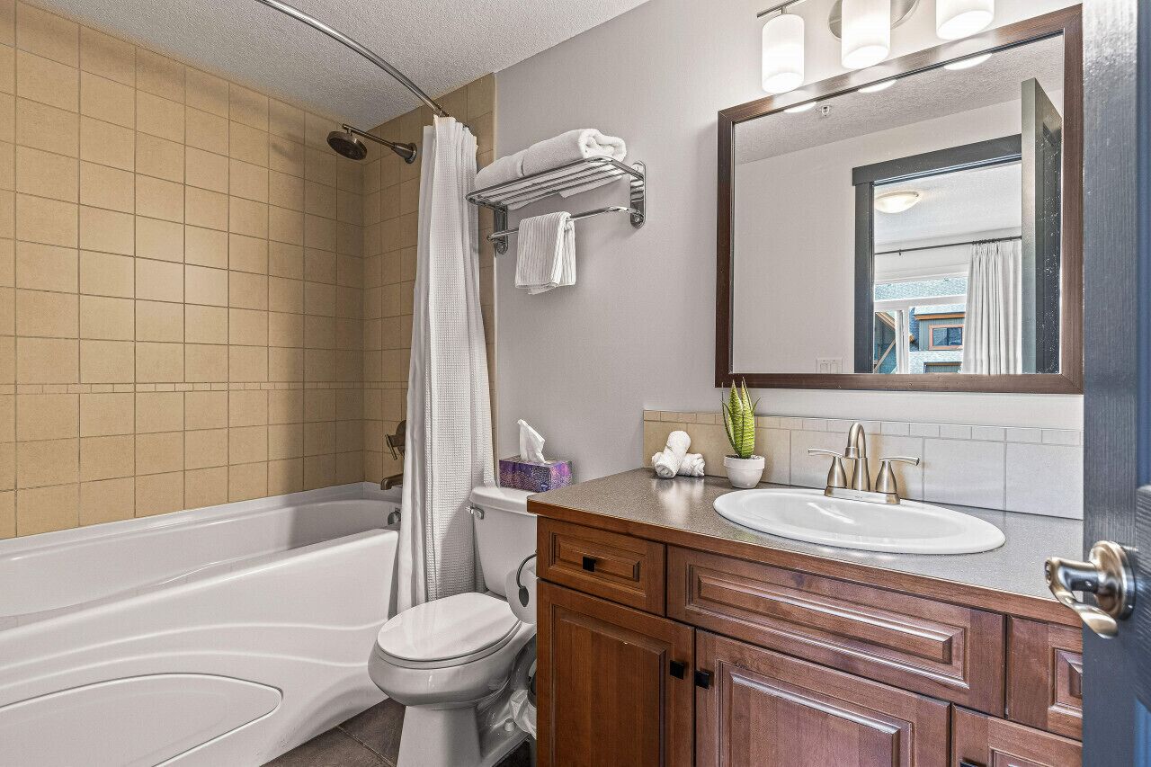 Une salle de bain avec une baignoire, des toilettes, un meuble-lavabo et un grand miroir.