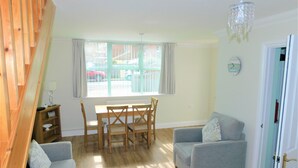 A living room with a dining table, two sofas, a chandelier, and a window with curtains. - The Annexe on Morris Street -  an annexe that sleeps 3 guests  in 2 bedrooms (Sheringham)