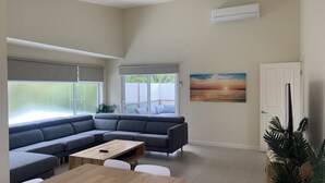 A modern living room with a sectional sofa, a coffee table, and a painting of a sunset. - Contemporary On Cuttriss - Inlet Side (Inverloch)