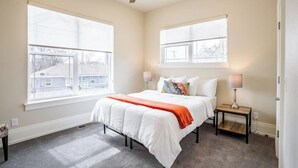 Una camera da letto con un letto, due comodini, una ventola a soffitto e ampie finestre.