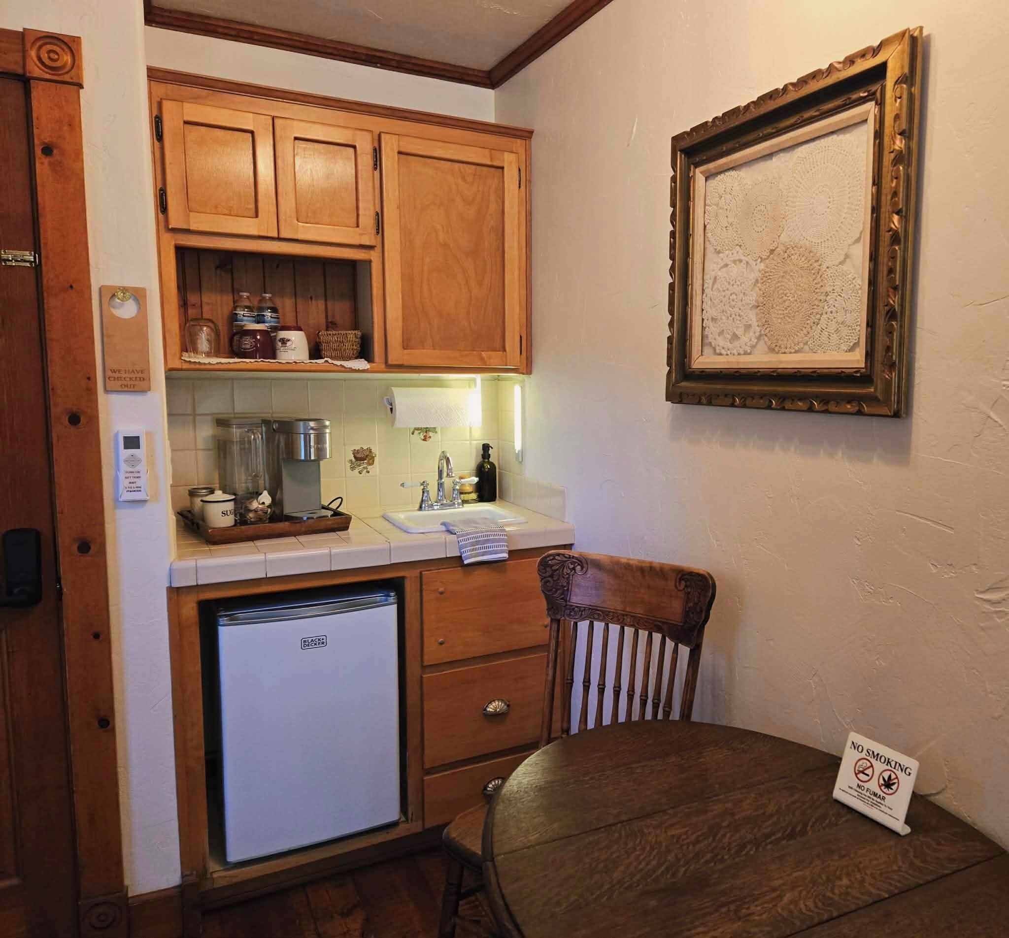 Eine kleine Küche mit Holzausstattung, einem Kühlschrank und einem Essbereich mit einem Stuhl.
