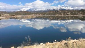 A calm lake reflecting snow-capped mountains under a clear sky.