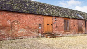A brick building with a wooden door, a small window, and a chimney. - Cider House at Oosland Barns - sleeps 4 guests  in 2 bedrooms (Bidford-on-Avon)