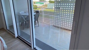 A balcony with a glass door, a small table, and two chairs. - Nice apartment 4 people in Hennebont wifi -  near Lorient 3 stars (HENNEBONT)