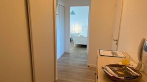 A narrow hallway leading to a bedroom with a bed and a bedside table. - Nice apartment 4 people in Hennebont wifi -  near Lorient 3 stars (HENNEBONT)