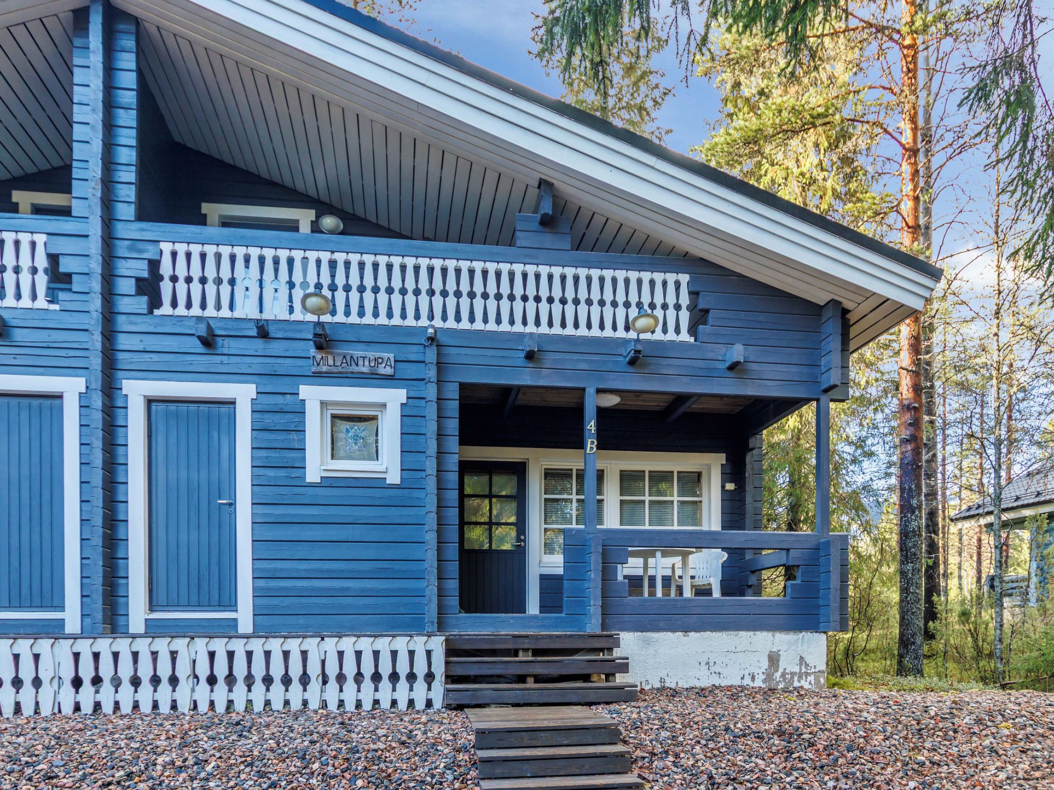 A two-story log cabin with a balcony and a covered porch.