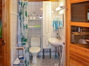 Bathroom features a toilet, sink, and shower curtain, along with a shelf for toiletries and a mirror.