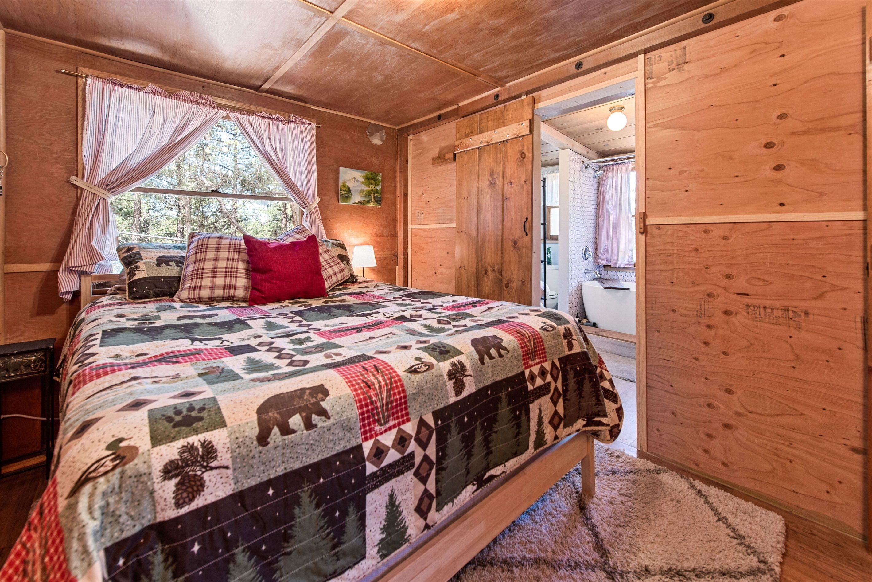 Un dormitorio acogedor con una cama grande, una puerta de madera y una ventana con cortinas.