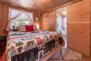 A cozy bedroom with a large bed, a wooden door, and a window with curtains.
