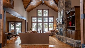 Una sala de estar amplia con techo alto, ventanas grandes, chimenea y un rincón de estar acogedor.