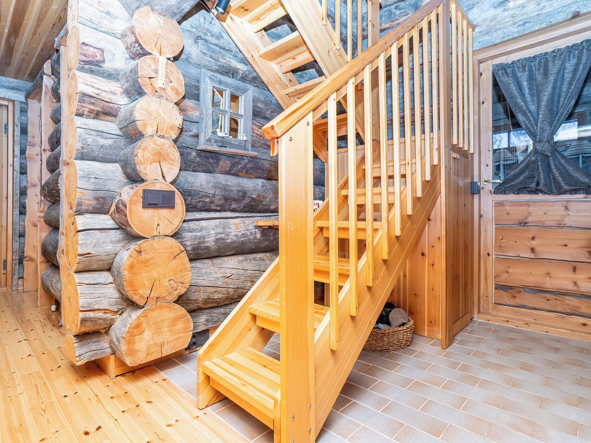 A wooden staircase with a handrail leading to a loft area with a window.