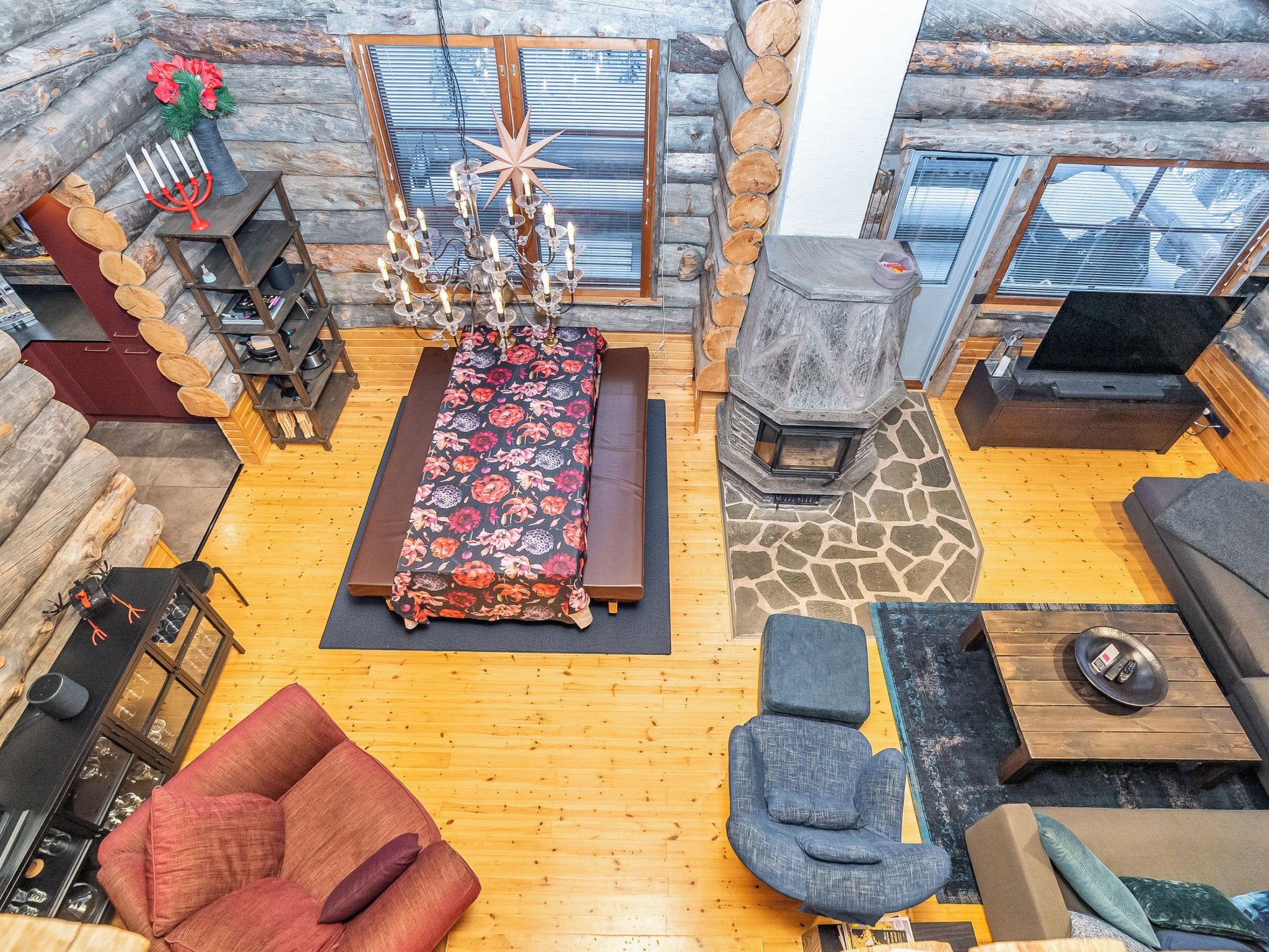 L’intérieur d’une cabane en rondins, avec une cheminée centrale, un canapé, une table à manger et une bibliothèque.