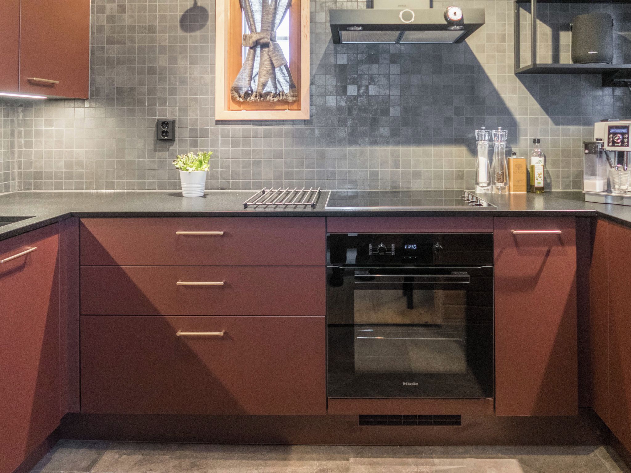 Una cocina moderna con lavavajillas integrado, extractor de acero inoxidable y salpicadero azulejado.