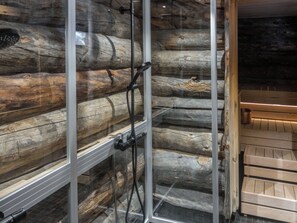 A glass-enclosed shower with a wooden log cabin interior.