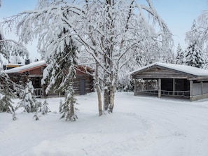A snow-covered cabin with a wooden exterior and a metal roof, surrounded by snow-laden trees. - Ruka-rokova 2 by Interhome (Kuusamo)