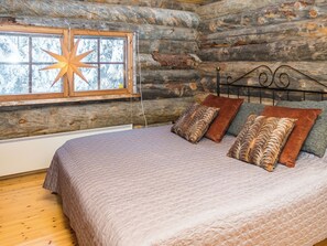 A log cabin bedroom with a bed, pillows, and a window.