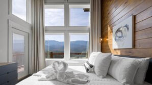 Una camera da letto con un'ampia finestra, un letto con biancheria bianca e un quadro appeso al muro.