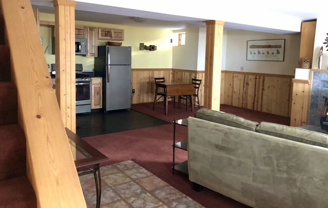 A kitchen with wooden cabinets, a refrigerator, and a dining area with a table and chairs.