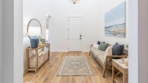 A modern living room with a wooden floor, a beige sofa, a console table with a lamp, a rug, and a painting on the wall. - Destination Ledges Utah (St. George)