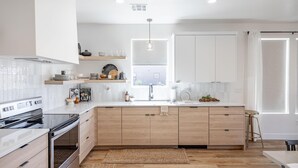 A modern kitchen with white cabinetry, a built-in oven, and a large island with a sink. - Destination Ledges Utah (St. George)
