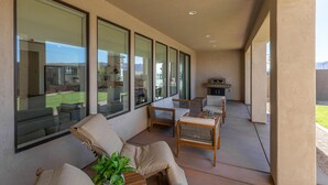 A spacious patio with large windows, outdoor furniture, and a grill area. - Destination Ledges Utah (St. George)