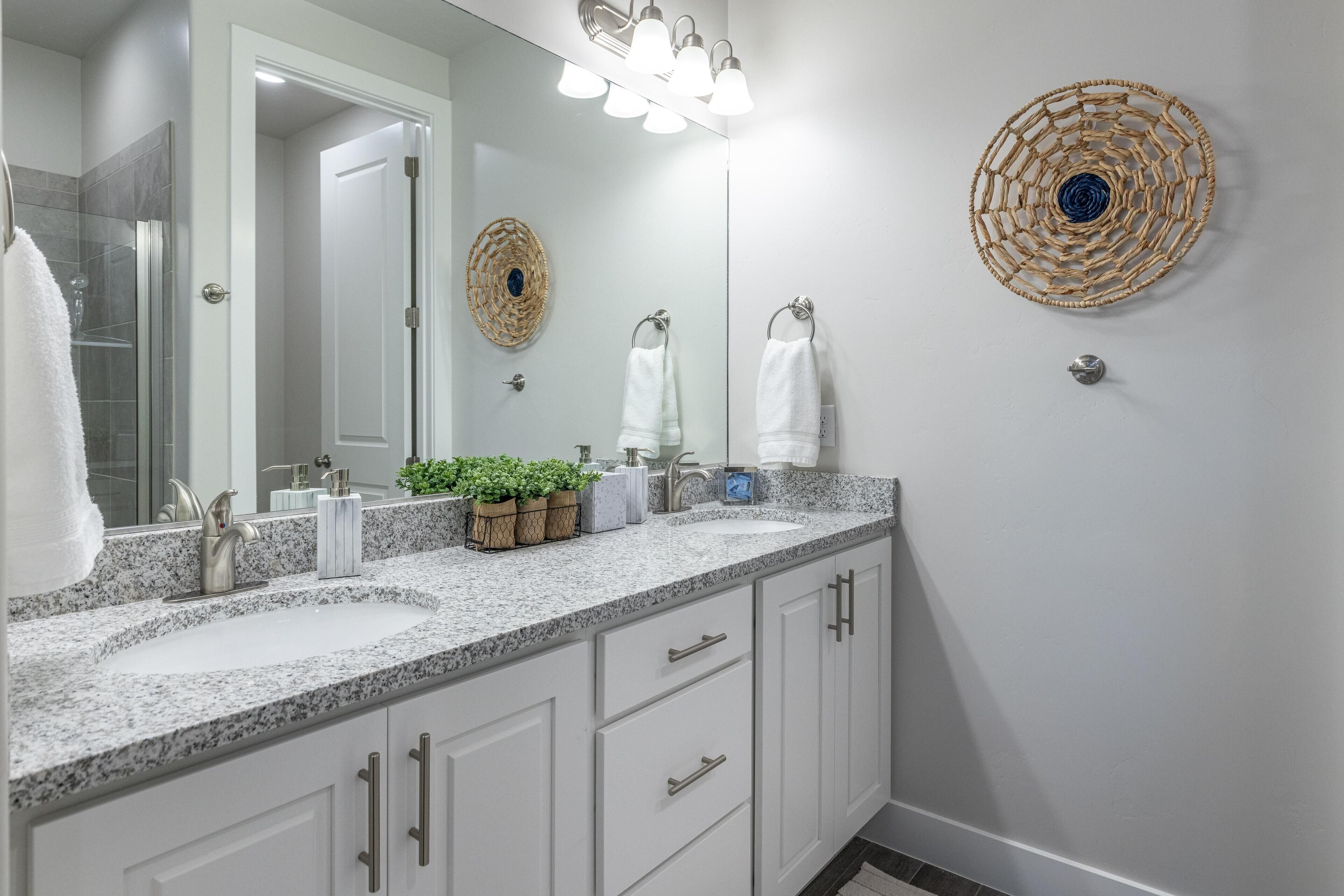 A modern bathroom with two sinks, a shower, and a vanity with drawers.
