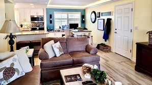 A living room with a brown sofa, a coffee table, and a ceiling fan. - Steps from Beach, Gorgeous Sunset Views, Recently Renovated, 2BD/2BTH, Sleeps 4 (Fort Myers Beach)