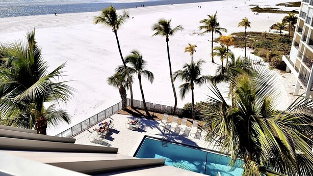 A resort with a pool, palm trees, and a beach view. - Steps from Beach, Gorgeous Sunset Views, Recently Renovated, 2BD/2BTH, Sleeps 4 (Fort Myers Beach)