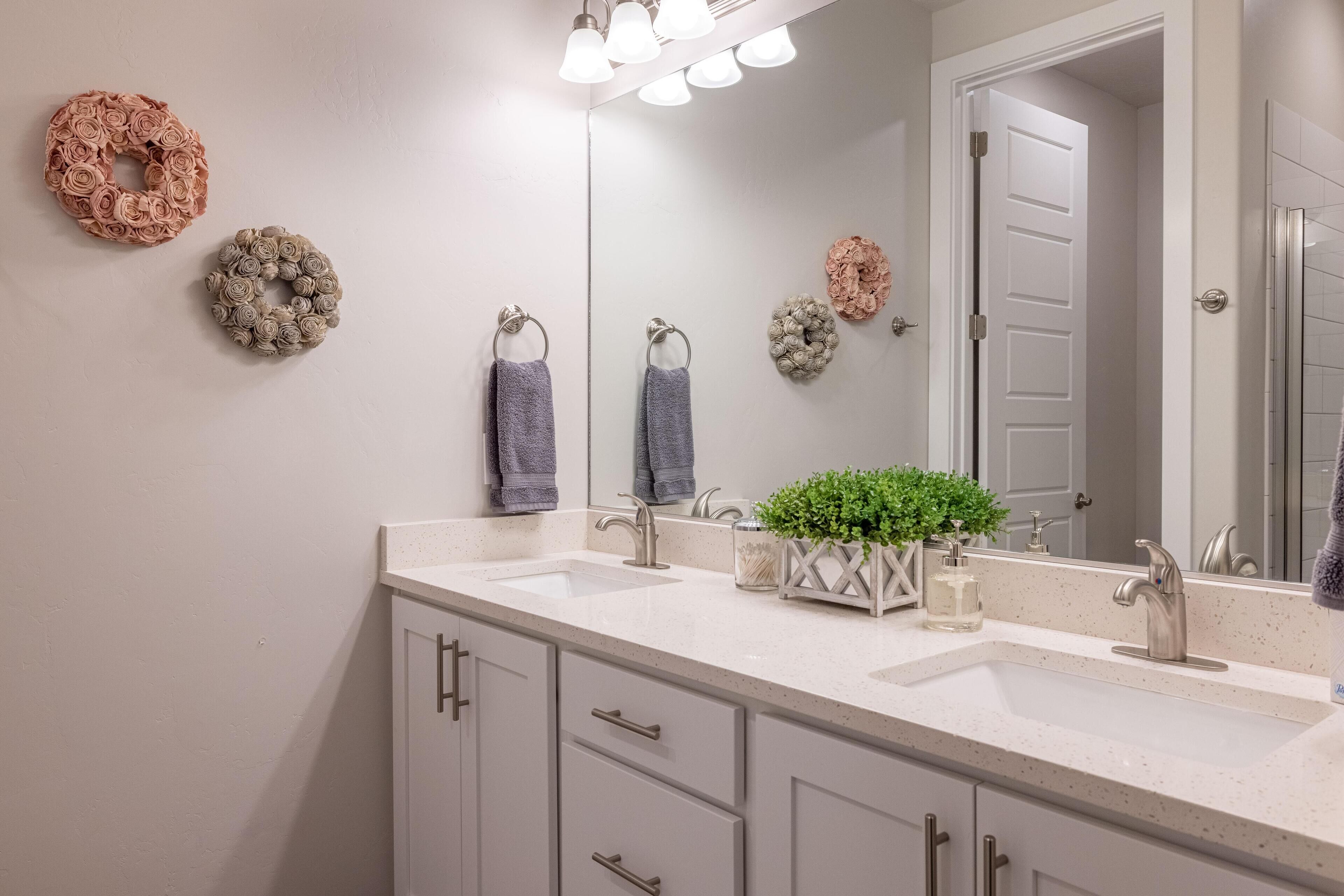 Une salle de bain avec deux lavabos, un miroir et des couronnes décoratives accrochées au mur.