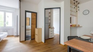 A modern room with a wooden floor, a bed, a desk, and a dining area with a table and chairs. - GuestHost - City Life & MiCo Cosy and Functional Apartment (Milano)