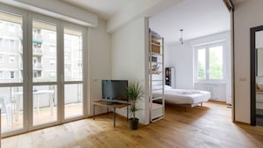A modern apartment with a balcony, a TV, a bed, and a small table with a plant. - GuestHost - City Life & MiCo Cosy and Functional Apartment (Milano)