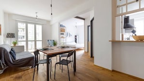 A modern apartment with a dining area, a sofa, a kitchen, and a large window. - GuestHost - City Life & MiCo Cosy and Functional Apartment (Milano)