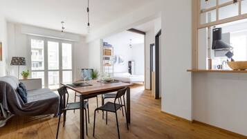 Eine moderne Wohnung mit Essbereich, einer Couch, einer Küche und einem großen Fenster.