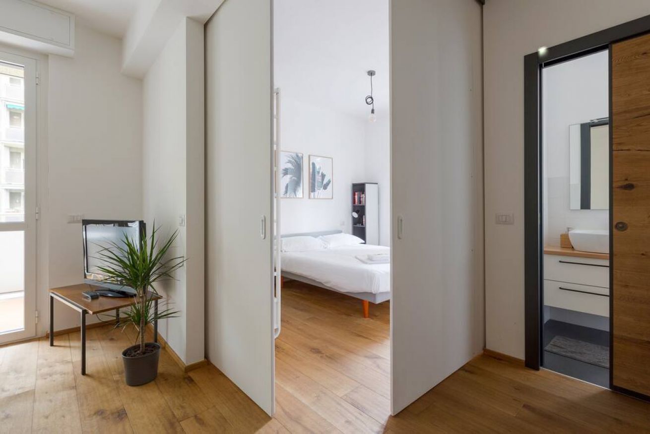 Ein modernes Schlafzimmer mit einem Bett, einem Nachttisch und einer Topfpflanze.