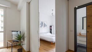 A modern bedroom with a bed, bedside table, and a potted plant. - GuestHost - City Life & MiCo Cosy and Functional Apartment (Milano)