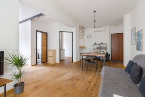 A modern living space with a dining area, a sofa, and a potted plant.
