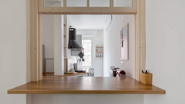 A kitchen with a wooden countertop, a black range hood, and a view into the adjacent dining area. - GuestHost - City Life & MiCo Cosy and Functional Apartment (Milano)