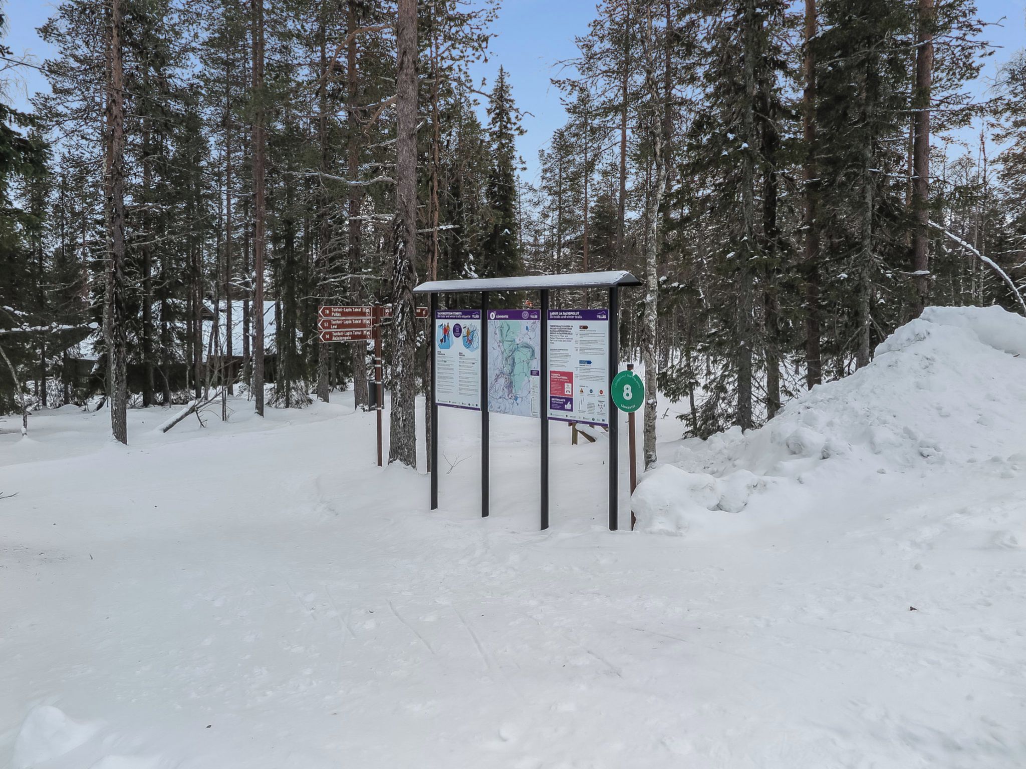 A snow-covered outdoor area with informational signs and a shelter.