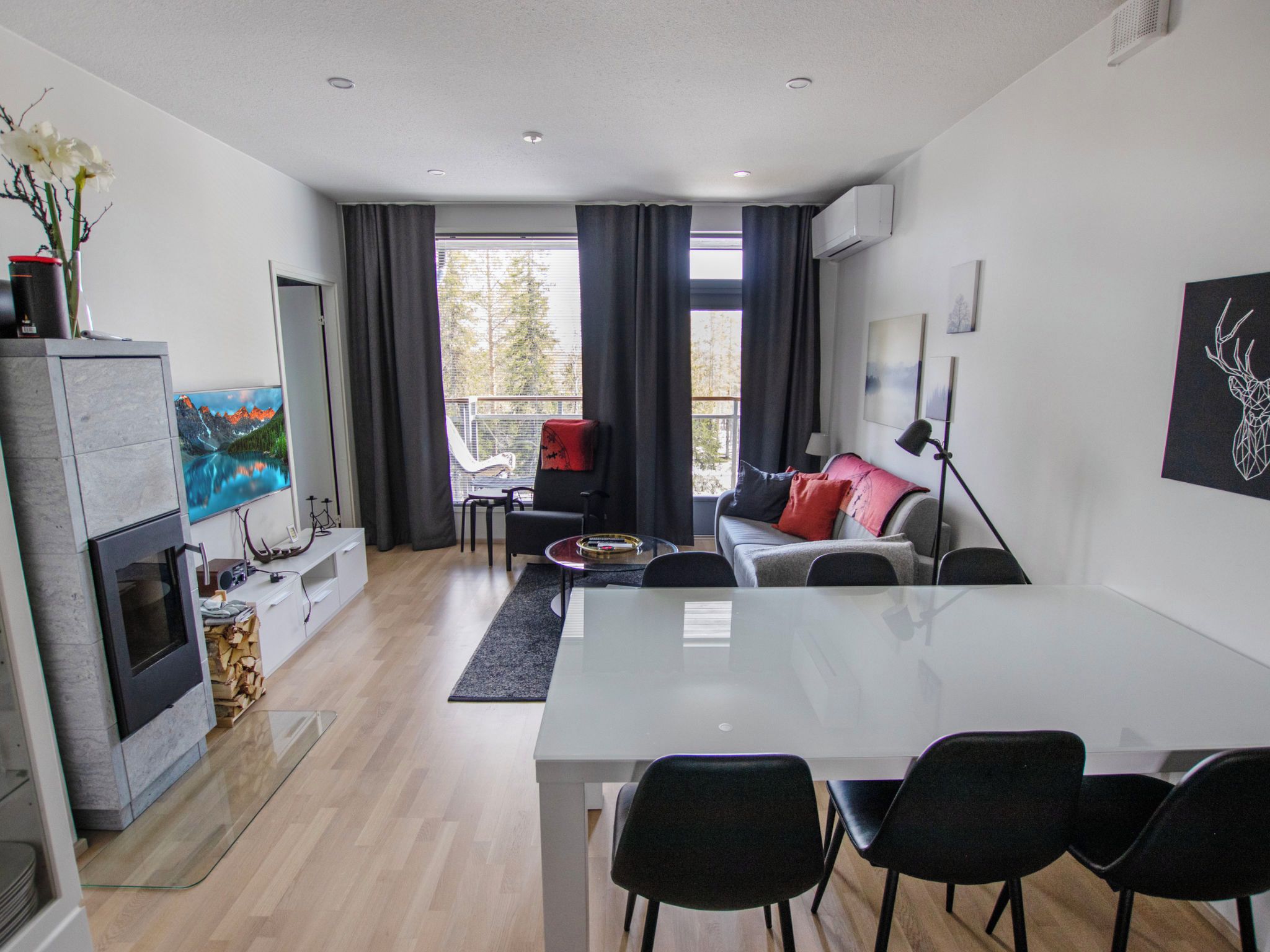 A modern living room with a dining area, a fireplace, and a large window with curtains.