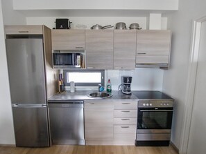 A compact kitchen with a refrigerator, microwave, coffee maker, and oven. - Ylälänsi 3 as 9 by Interhome (Ylläsjärvi)