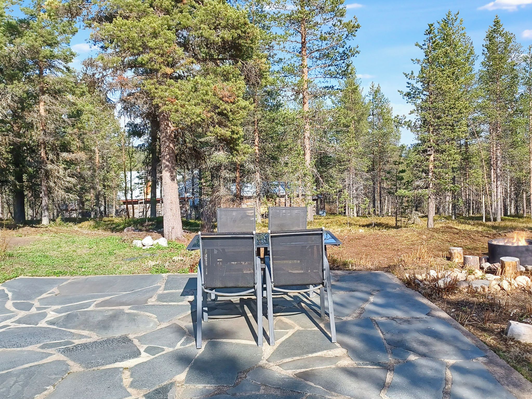 Une terrasse extérieure avec un sol en pierre, deux chaises en métal et une table.