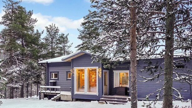 A small, single-story cabin with a porch and a covered outdoor seating area, surrounded by snow-covered trees. - Riekkotupa by Interhome (Enontekiö)