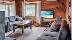 A cozy cabin-style room with a large window, a television, a sofa, and a coffee table. - Riekkotupa by Interhome (Enontekiö)