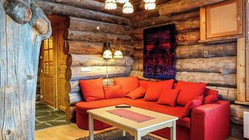 A log cabin interior with a red sofa, a small table, and a chandelier.