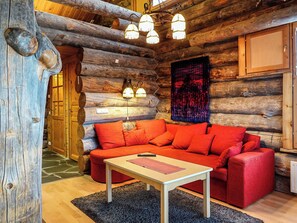 A log cabin interior with a red sofa, a small table, and a chandelier. - Sallanhelmi c2 by Interhome (Salla)